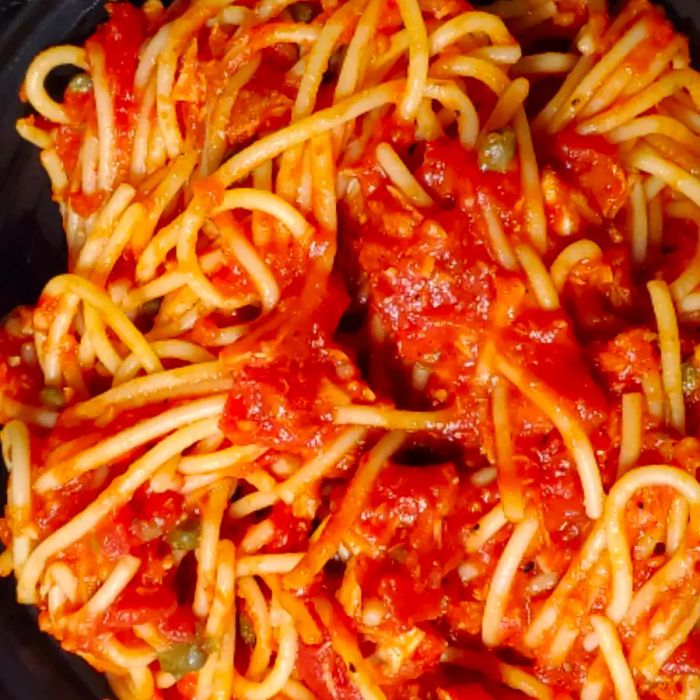 Close-up shot of Spaghetti al Tonno, pasta with a rich red sauce in a skillet