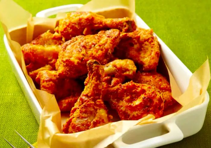 Golden Fried Chicken served in a white pan with a fork on a napkin.