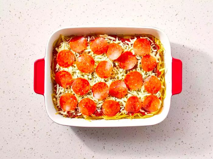 Spaghetti Pizza ingredients layered in a casserole dish