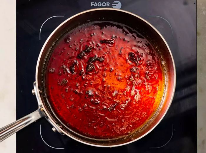 A saucepan with a simmering sauce mixture, taking on a rich brown hue.