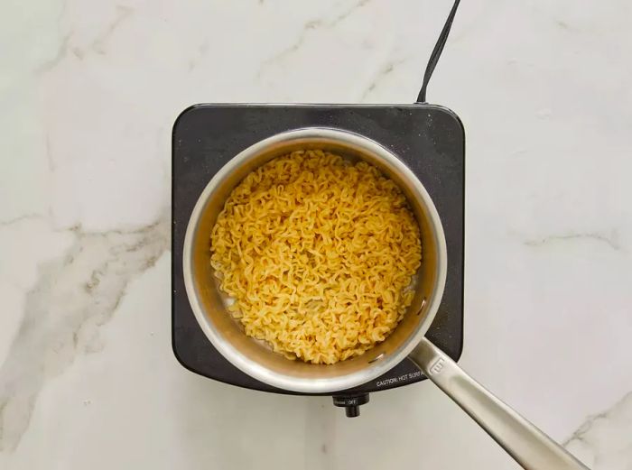 Top-down view of ramen cooking in a pot