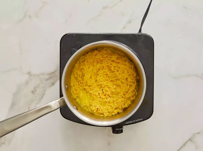 Top-down view of cheesy ramen simmering in a pot