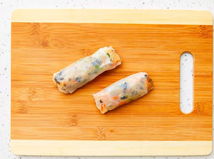 The filling is placed onto the softened rice paper and rolled up securely.