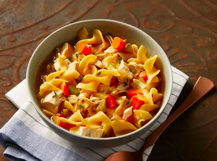 A high-angle view of a bowl of chicken noodle soup with carrots.