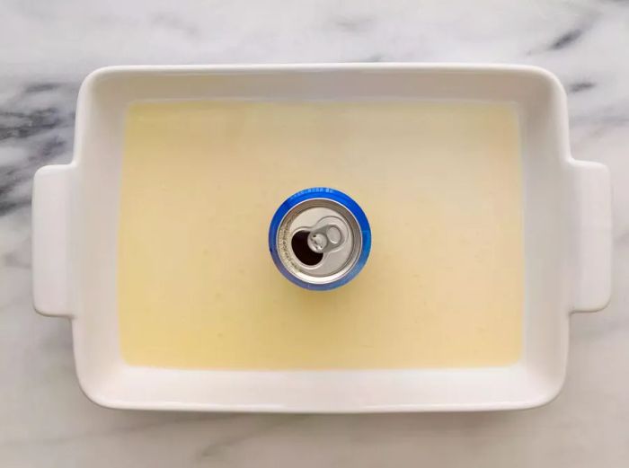 A baking dish with beer and a beer can placed in the center