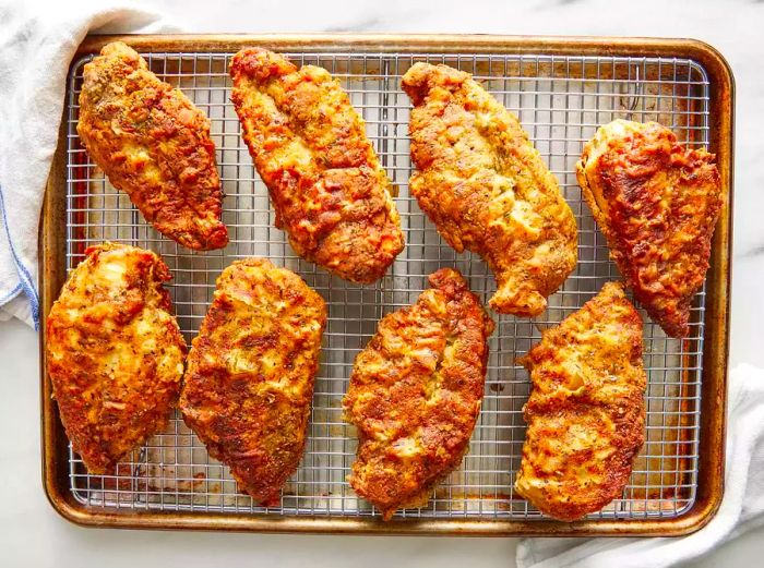 Bird's-eye view of fried breaded chicken breasts resting on a wire rack