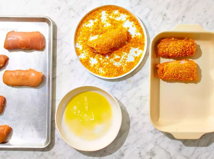 Melted butter and cereal crumbs placed in shallow bowls, each chicken roll dipped in butter and rolled in crumbs, then transferred to the baking dish.