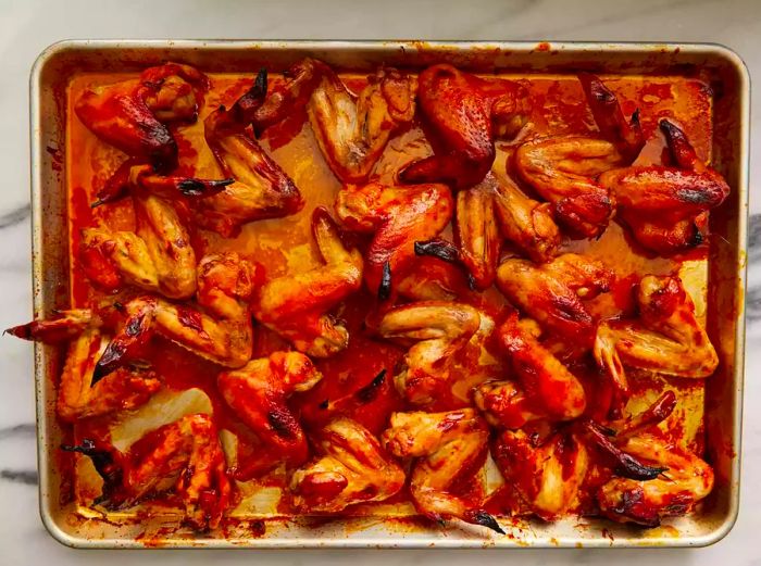 Top-down view of cooked chicken wings, coated in sauce.