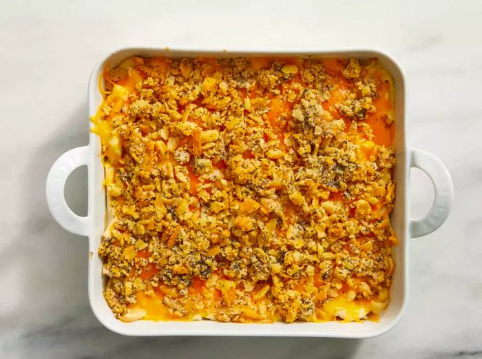 An unbaked poppy seed chicken casserole, topped with crumbled crackers and a sprinkling of poppy seeds