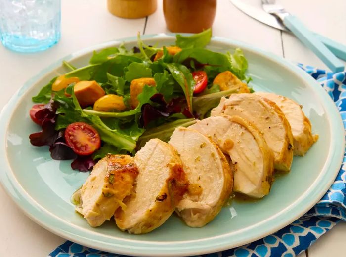 A plate of sliced beer can chicken, served alongside a fresh, simple salad