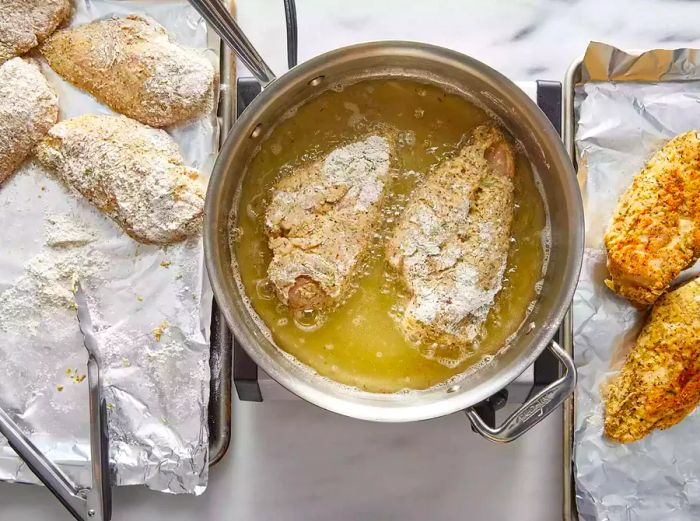 Bird's-eye view of breaded chicken breasts frying in hot oil