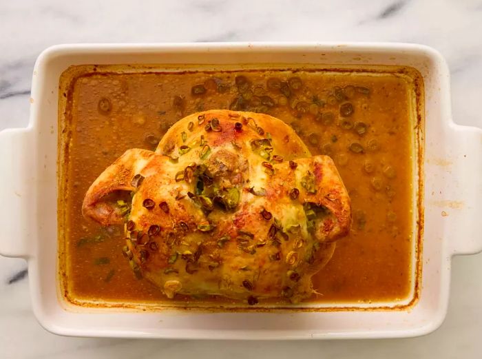 A baking dish with a perfectly baked beer can chicken