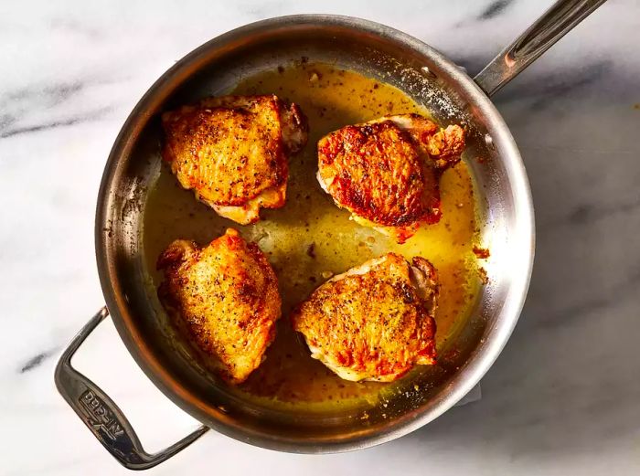 Lemon butter sauce poured over the chicken, then baked in the preheated oven until fully cooked.