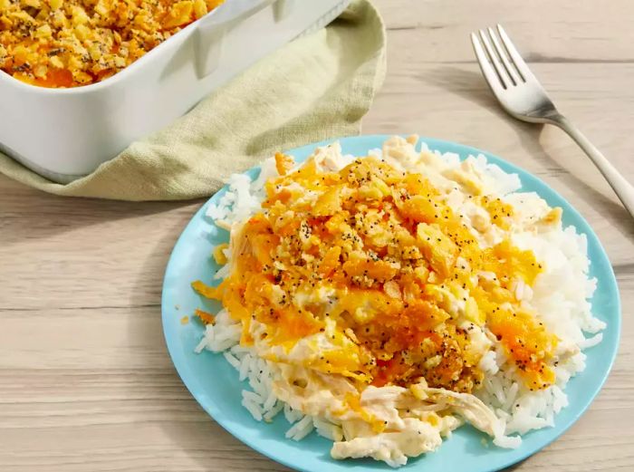 A serving of poppy seed chicken casserole, plated over a bed of white rice