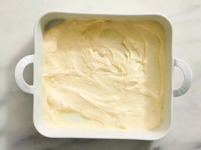 A baking dish with a layer of condensed soup and sour cream mixture