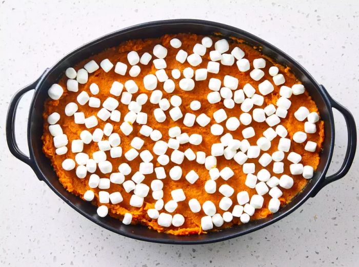 A baking dish filled with mashed sweet potatoes, topped with mini marshmallows