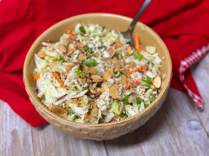 Ramen coleslaw served in a beige bag on a red tablecloth.