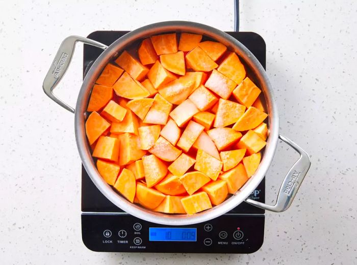 A large pot of salted water with peeled sweet potato chunks