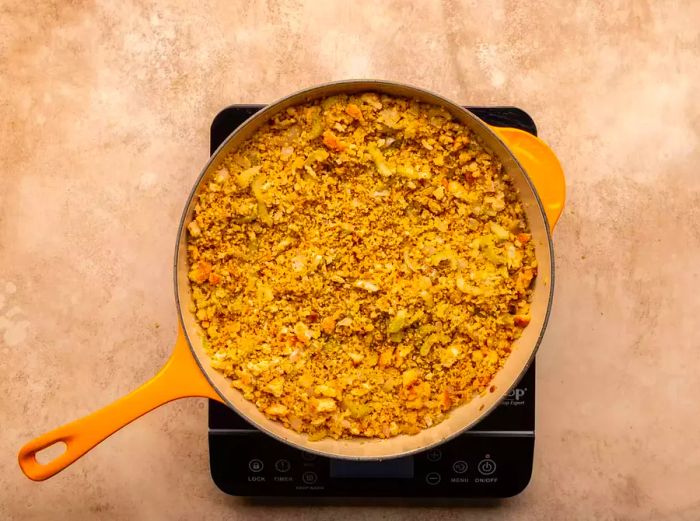 Bread crumbs, salt, poultry seasoning, pepper, thyme, and sage added to the skillet for cooking.