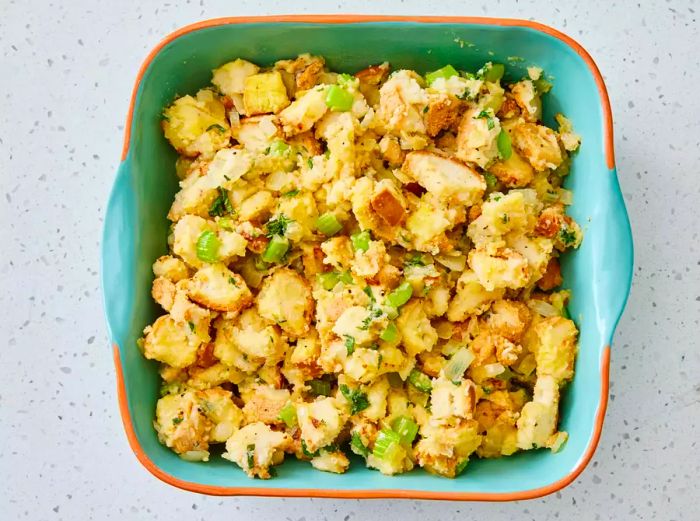 A baking dish filled with gluten-free bread cubes tossed in the onion-sage mixture