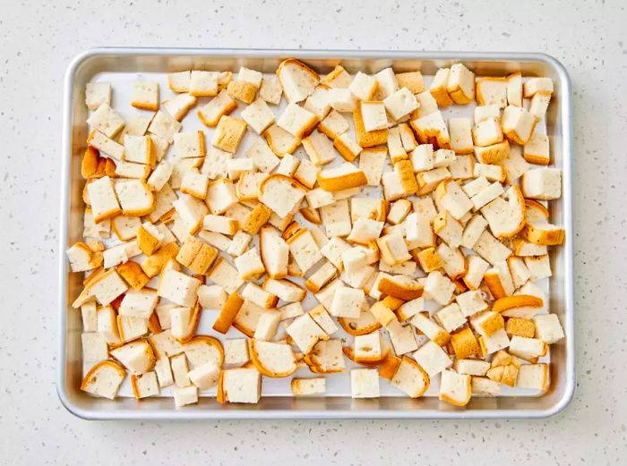 A baking sheet with cubed gluten-free bread ready for toasting