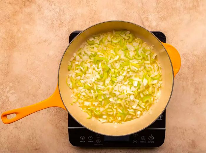 Onion, celery, and butter simmering together in a deep skillet.