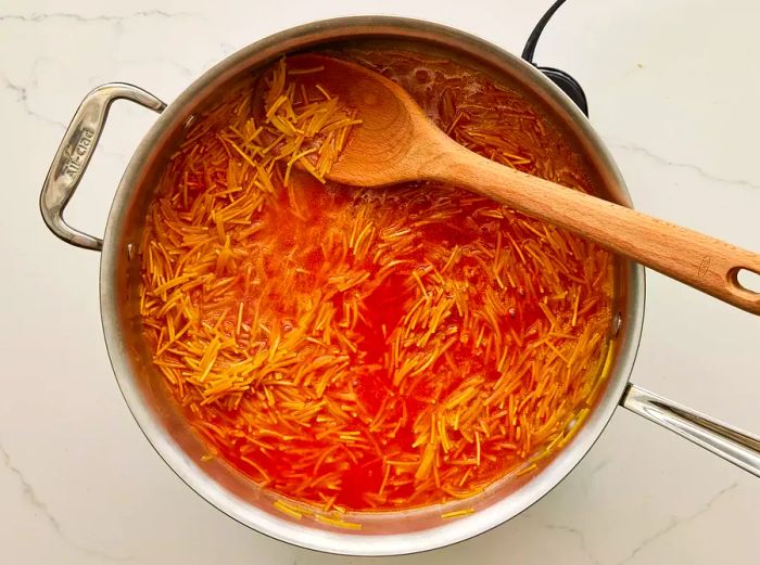 A pan of fideo pasta cooking in a blend of water and tomato sauce