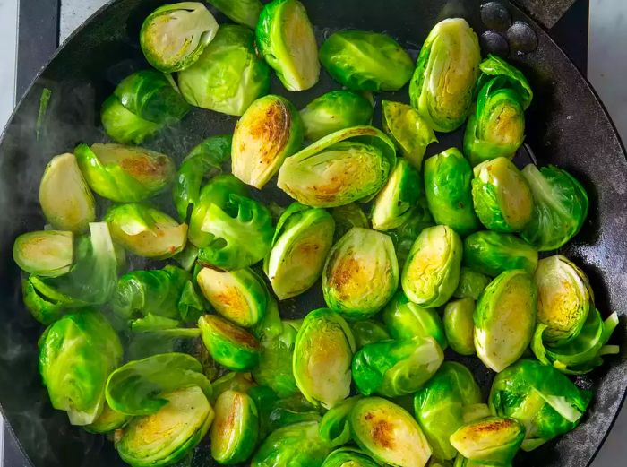 Brussels sprouts in the skillet with the cut sides facing down.