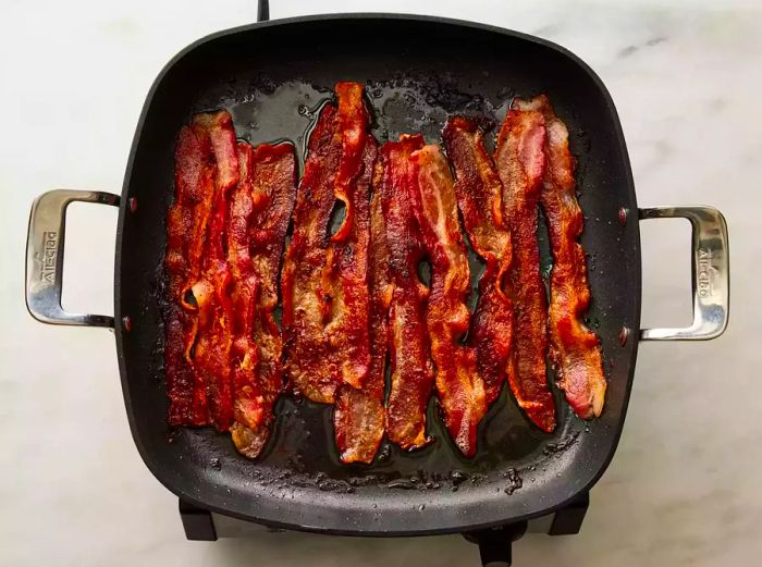 Bacon sizzling in a skillet, browning to perfection.