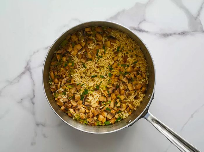 A top-down view of a small pot containing perfectly cooked mushroom rice.