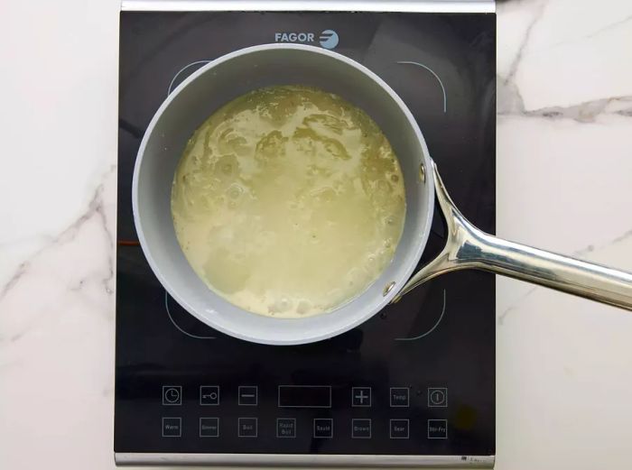 A small saucepan with sugar, cornstarch, vinegar, and water gently simmering together