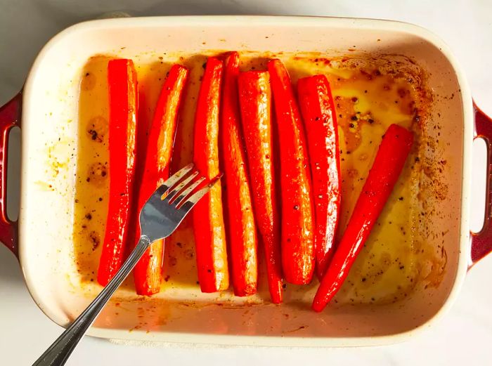 A close-up shot of roasted honey carrots being tested with a fork.