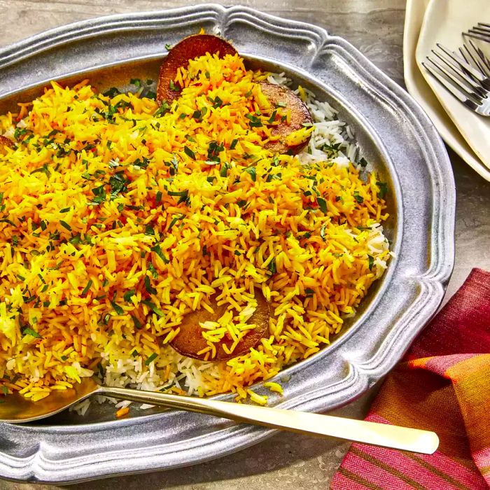 A bird's eye view of a family-style serving of Persian rice, beautifully arranged with golden potatoes and vibrant saffron rice.