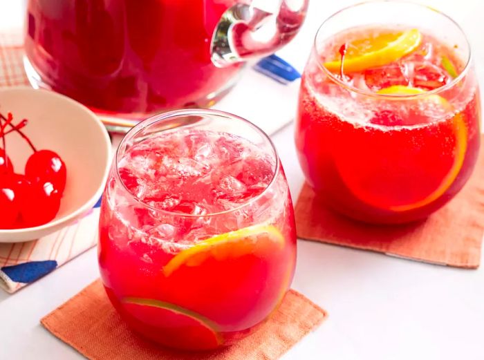 A high-angle view of two glasses of sangria with the remaining sangria in a pitcher behind them.