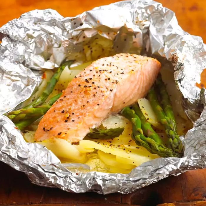 Salmon fillet wrapped in foil with roasted potatoes and asparagus