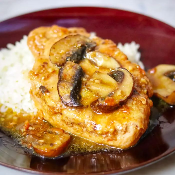 A top-down view of a plate of pork marsala served with rice