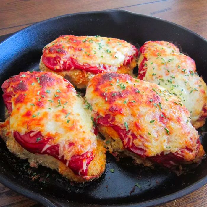 Four baked breaded chicken breasts, topped with tangy red sauce and melted mozzarella cheese, served in a cast-iron skillet