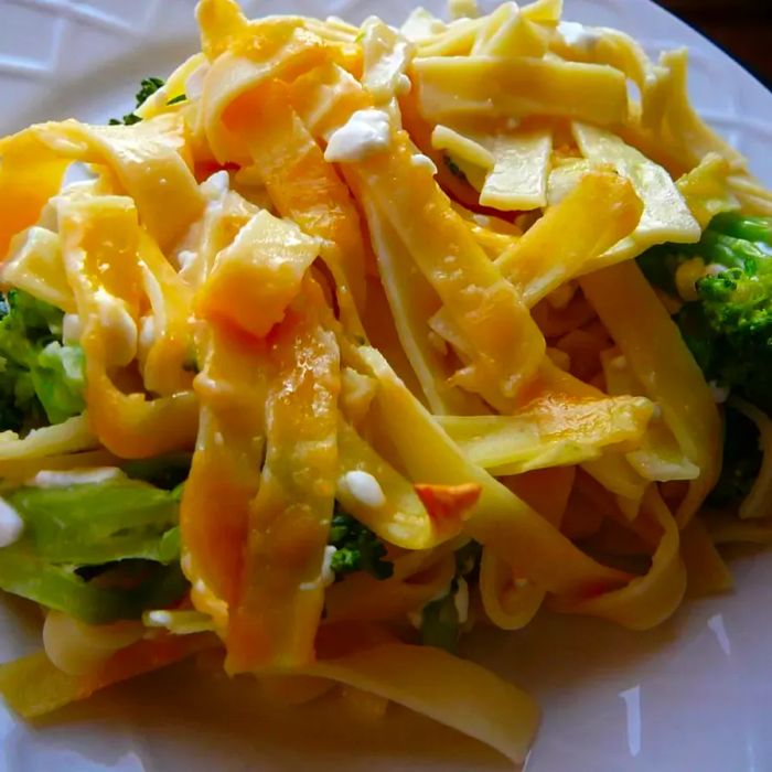 Broccoli, noodles, and cheese casserole served on a white plate