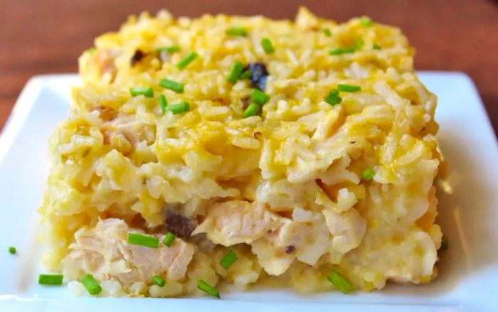 A close-up of a square serving of casserole, garnished with freshly chopped chives