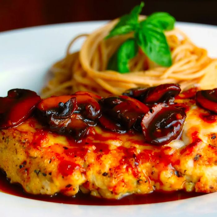 Chicken Marsala with mushrooms served over pasta on a plate