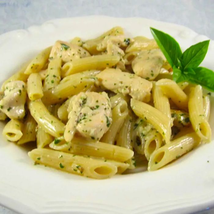 Mid-angle view of a bowl of penne pasta with chicken and pesto