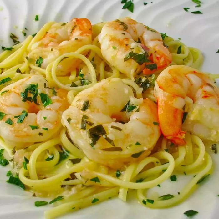 Pasta with shrimp, garnished with fresh parsley, served on a white plate