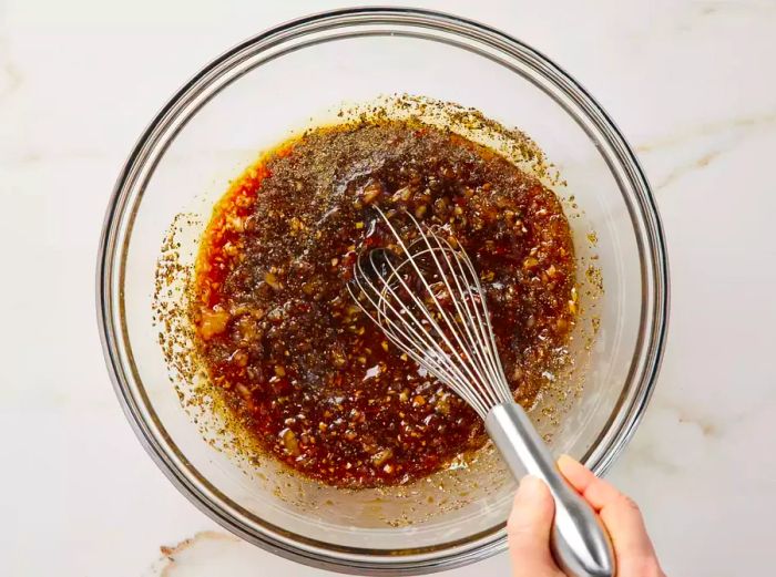 A large bowl of soy-sesame marinade being mixed together with a whisk