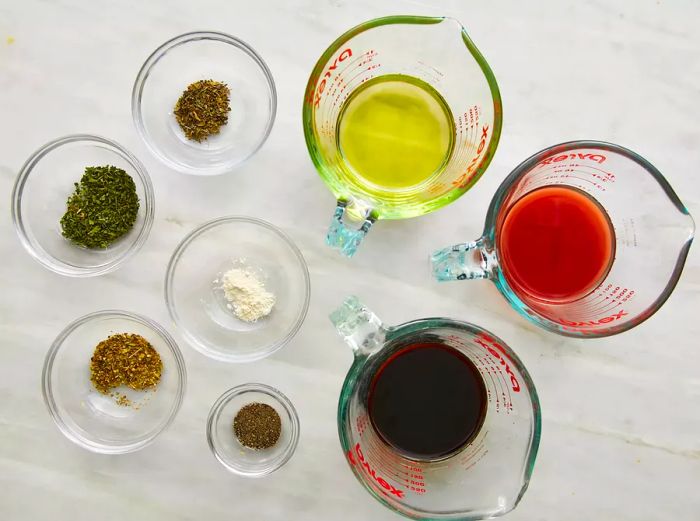 A variety of ingredients for the chicken marinade arranged in glass bowls on the counter.