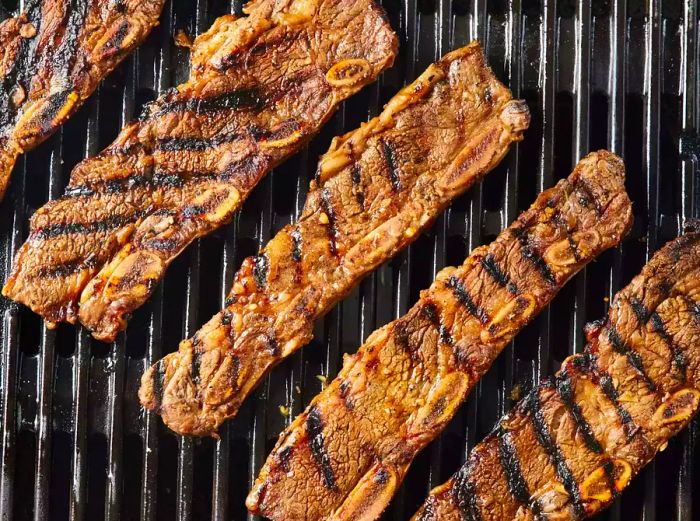 Grilled Korean BBQ short ribs sizzling on the grill grates