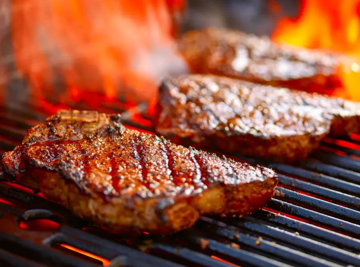 Steaks sizzling on the grill, surrounded by flames.