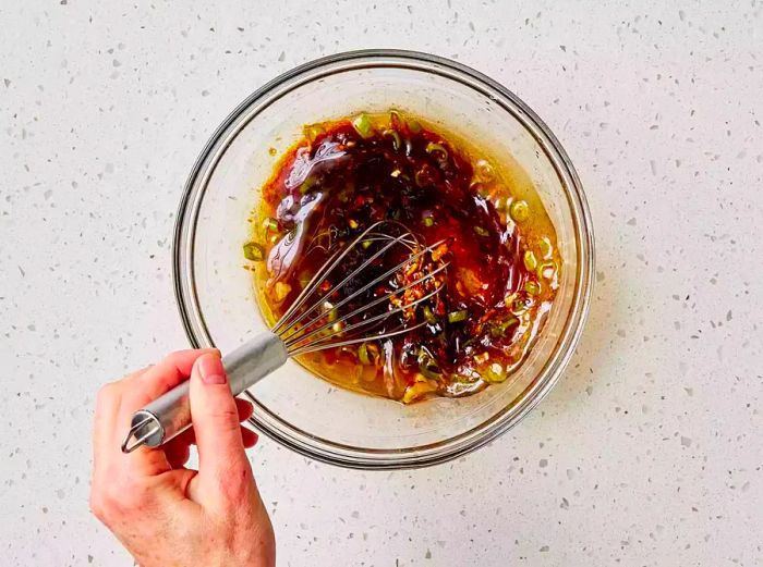 A small bowl of soy marinade being whisked together