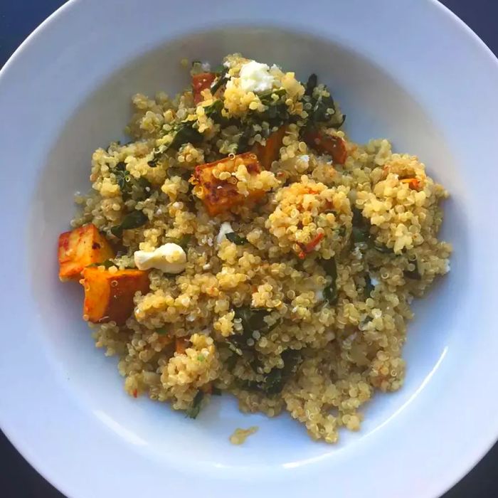 A top-down view of a bowl filled with coconut quinoa topped with harissa-roasted sweet potatoes