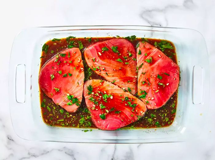 Tuna steaks placed in the marinade dish.