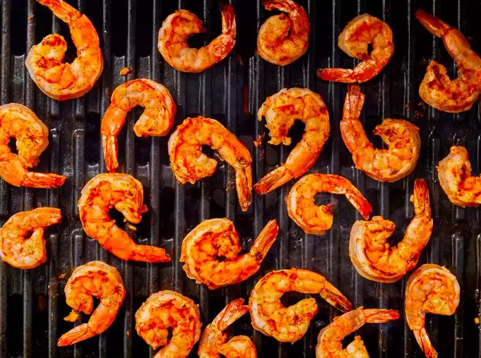 Shrimp coated in spicy garlic sauce grilling on the grate